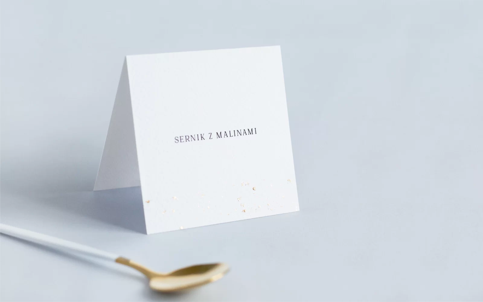Białe karteczki z nazwami dań na wesele pozłacane